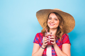 smiling woman drink red juice. studio portrait with blue background and copy space