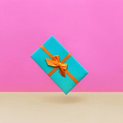 Gift box Trendy styled photo Blue gift box is hanging in the air against the background of a purple wall Front view Modern pop art photo with space for text