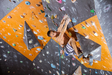 Young male rock climber in indoor climbing gym