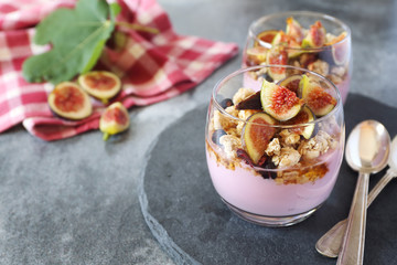 Two glasses of fruit yogurt with granola, figs and honey