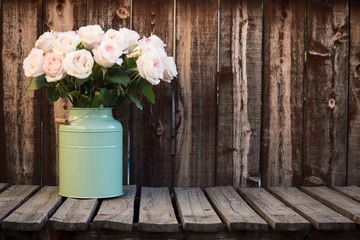 Schilderijen op glas Pink roses in a green bucket style container on a wooden plank table. © Mary Lynn Strand