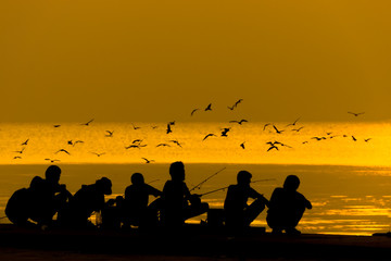 Fototapeta na wymiar Silhouettes of people fishing on a lake at sunset.