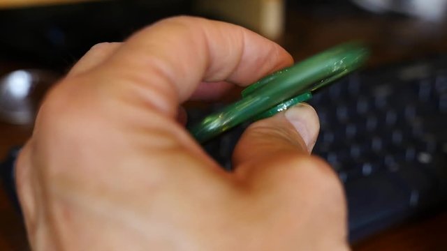 A bored office worker playing with a fidget spinner at his desk