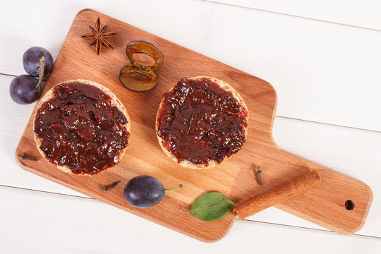 Fresh prepared sandwiches with plum marmalade or jam on wooden cutting board, breakfast concept