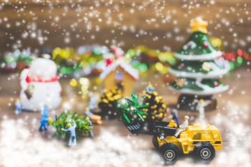 Creative concept with miniature people creating Christmas decorations on a wooden background.