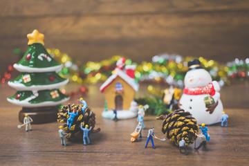 Creative concept with miniature people creating Christmas decorations on a wooden background.