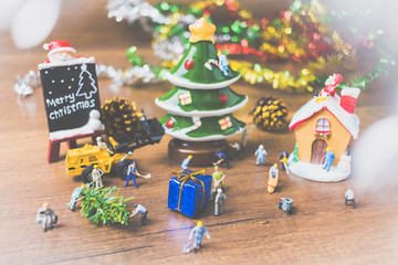 Creative concept with miniature people creating Christmas decorations on a wooden background.