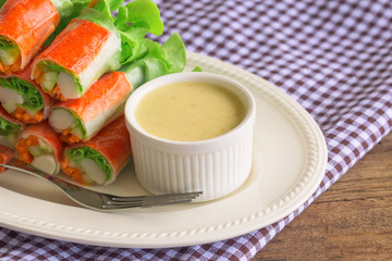 Fresh spring rolls with fresh vegetable and crab stick served with spicy salad cream dipping sauce. Rolls salad or fresh spring roll on white plate, healthy delicious food for appetizer or meal.