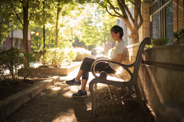 A woman sitting on a city park bench.