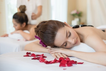 Obraz na płótnie Canvas Young beautiful woman getting hot stone massage in spa salon.