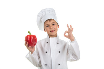 Boy in chef uniform making ok gesture and holding red pepper