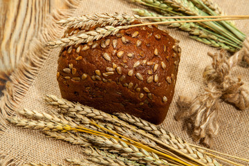 Black bread and wheat on a wooden background