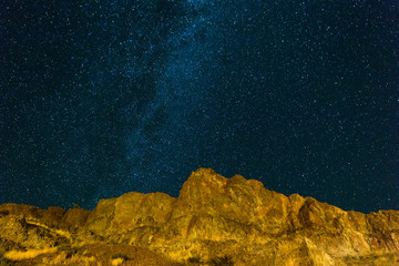 Naklejka premium Starry Night Sky over Rocky Landscape