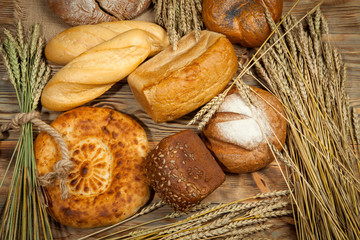 Rustic bread and wheat on the wooden background.