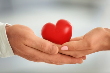 Lovely couple holding small red heart, closeup