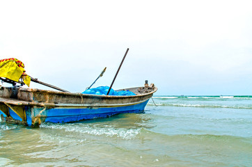 The sand beach and sea with fishing boat that parked on the beachfront with rock and reef in morning with sunrise, Beautiful sky with sea and fishing boat and rock with house in the seafront.
