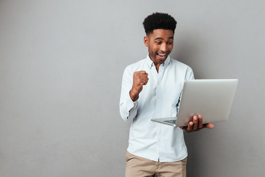 Excited happy afro american man looking at laptop computer