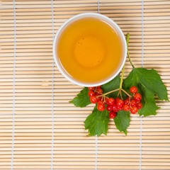 viburnum berries and cup of tea on bamboo table