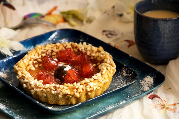 kleines Fruchttörtchen mit Mandelsplittern und einer Tasse Kaffee