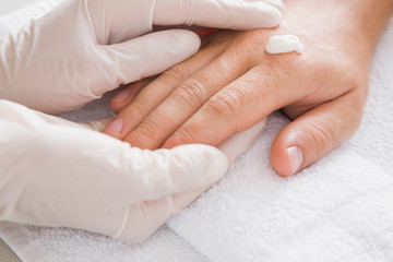 Hands in gloves with moisturizing cream cares about man's hands skin. Manicure beauty salon concept.