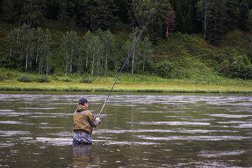 single fisherman on a calm river is autumn fishing