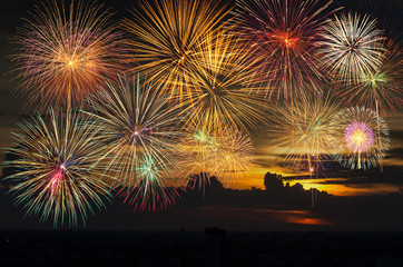 Fototapeta na wymiar Fantastic festive new years colorful fireworks on the evening sky with majestic clouds