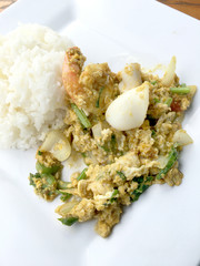 Stir-fried soft-shelled crab in curry and seafood in Curry Powder with thai jasmine rice in white dish on wooden table. (Poo-Pad-Phng-Ka-Ree Thai Food)