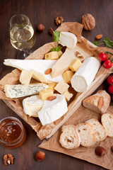 Variety of different cheese with wine, fruits and nuts. Camembert, goat cheese, roquefort, gorgonzolla, gauda, parmesan, emmental