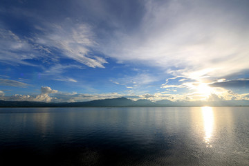 Beautiful sunset and evening sky with mountain and clouds and sunset reflected in the lake for background. Countryside Landscape Under Scenic Colorful Sky At Sunset Dawn Sunrise.