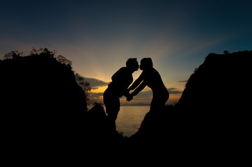 Silhouette of happy lover holding each other on the mountain over the sea and twilight sky, valentine lover concept