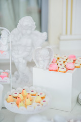 Little colorful cakes served on white boxes among figures of porcelain angels