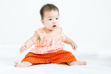 Portrait of adorable baby sitting on a white floor and smiling with copyspace