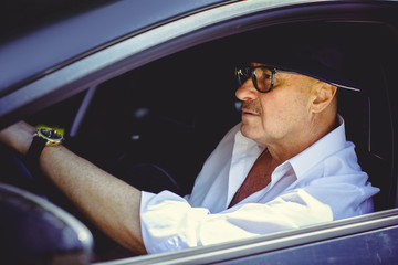 Older man in a hat rides in a car and enjoys life in adulthood. Pros and cons of life after 50-60s