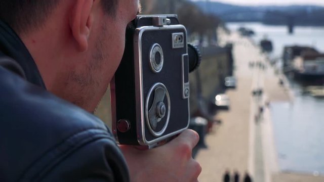 A man shoots a video of a boat at a port on a river