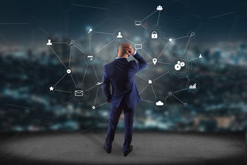 Businessman in front of a wall with a business network connection displayed on a futuristic interface with technology icon - Worldwide business concept