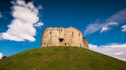 Fototapeta na wymiar Beautiful wide angle shot of the York Castle - Cliffords Tower - against a deep blue sky and volumetric clouds, Yorkshire, England, UK