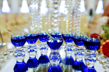 Glasses with blue drinks stand on mirror tray decorated with crystals