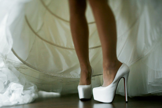 Bride puts on her shoes raising wedding dress up