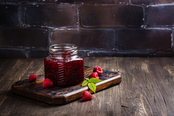 Raspberry jam in a glass jar and fresh raspberry. Vintage rustic style. Copy space