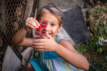 Happy little rural girl with a spinner in her hand holds a thumbs up.