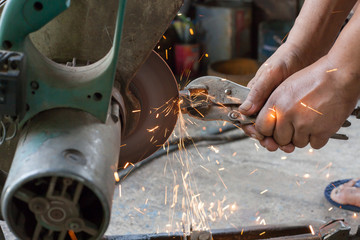 Worker cuts a metal pipe with sparks