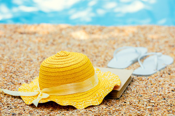 Beach scene. Sun straw hat, and flip flop sandals lying on sea coquina shells on the beach