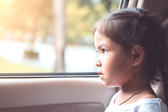 Cute Asian Little Child Girl Sitting In The Car And Look Out From The Car Window In The Sunset