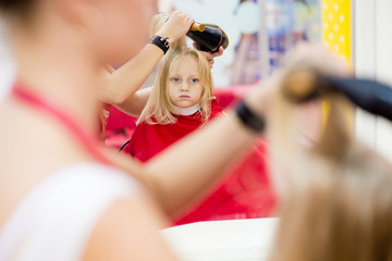 Little girl make a hairstyle in the beauty salon.