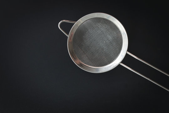 kitchen tools sieve flour or sugar filter top view on black background