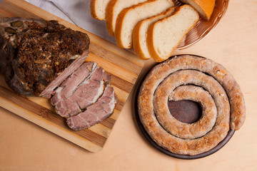 Roasted traditional homemade sausage with spices and herbs. Baked pork with herbs and spice on wooden board and and slices white wheat bread.