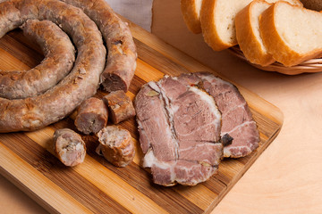 Sliced roasted traditional homemade sausage with spices and herbs. Baked pork with herbs and spice on wooden board and and slices white wheat bread.