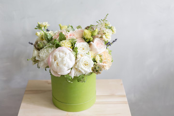 Beautiful tender bouquet of flowers in green box on light-gray background with space for text