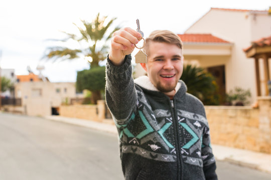 Young smiling man showing keys to new home. Real estate, apartment and people concept