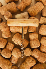 A lot of wine corks and corkscrew on the wooden background, top view.